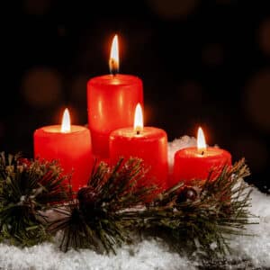 Kerze auf Tanne als Symbol für Adventsgrüße