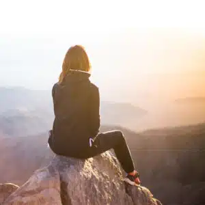 Frau, die auf einem Berg ins Weite blickt, als Symbol für Freiheit