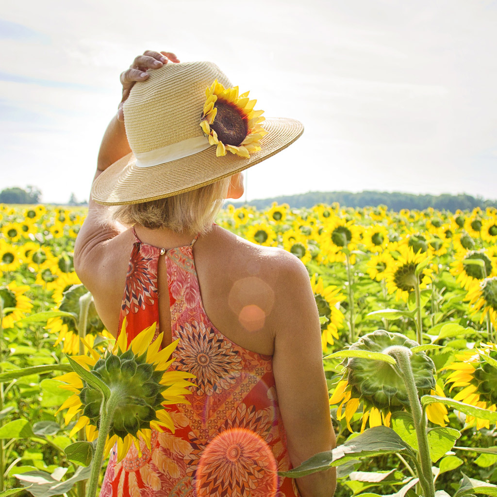 Frau in einem Sonnenblumenfeld als Symbol für Freude bzw. Lebensfreude