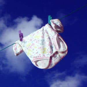 Strampler auf Wäscheleine als Symbol für Geburt