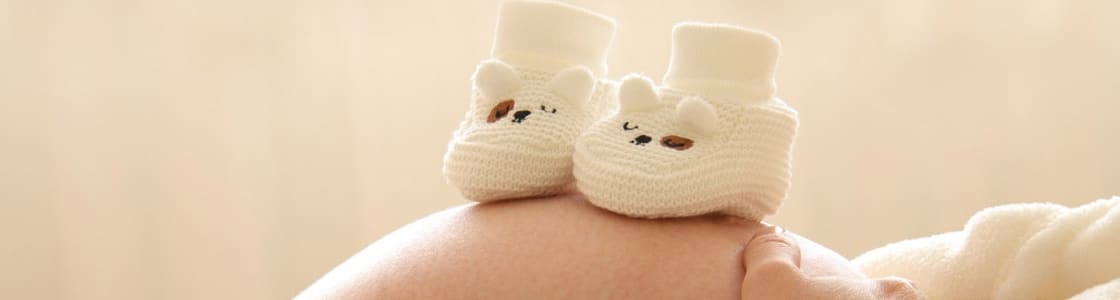Babyschuhe stehen auf Schwangerschaftsbauch