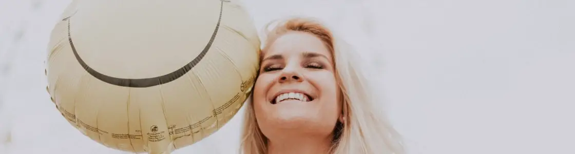 lächelnde Frau mit Smilie-Ballon