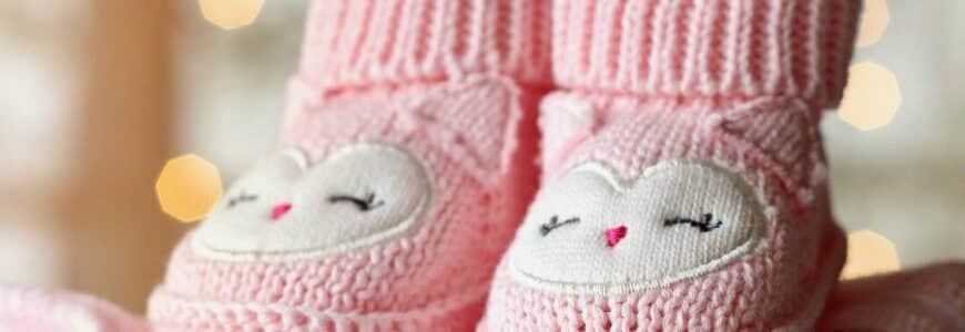 rosa Babyschuhe auf Kleiderstapel