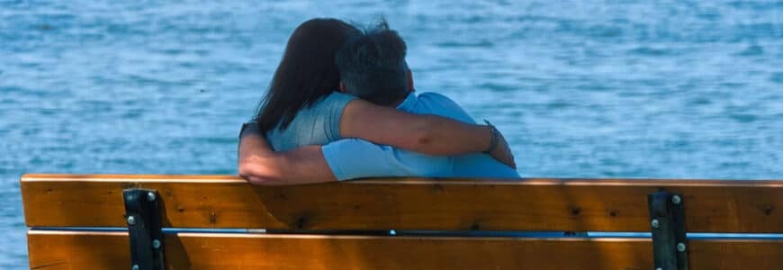 Paar kuschelt auf Bank am See