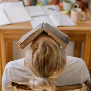 Frau mit Buch über Gesicht als Beispiel für Prokrastination