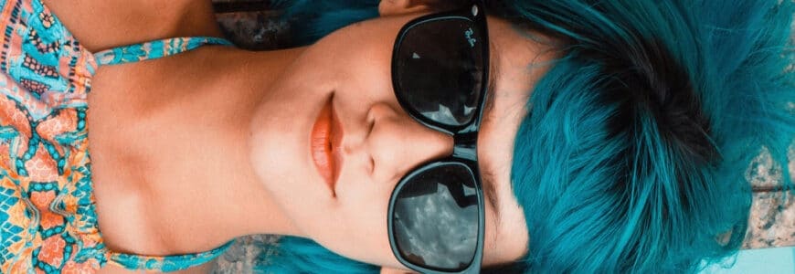 Frau mit blauen Haaren und Sonnenbrille sonnt sich