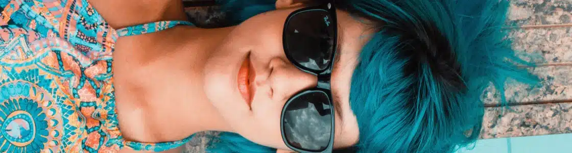 Frau mit blauen Haaren und Sonnenbrille sonnt sich