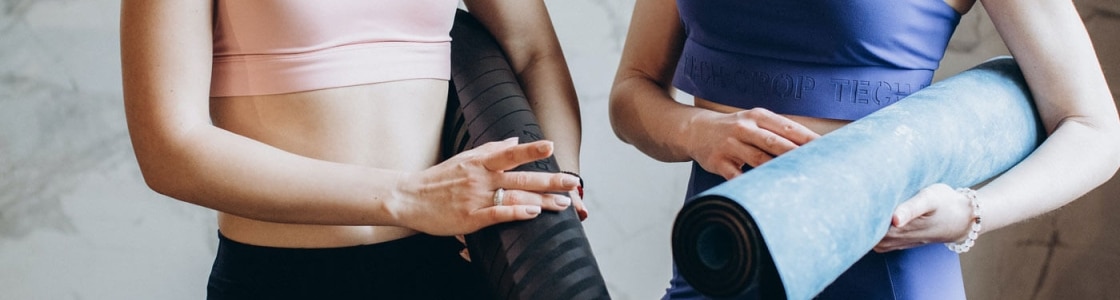 zwei Frauen tragen Yogamatten