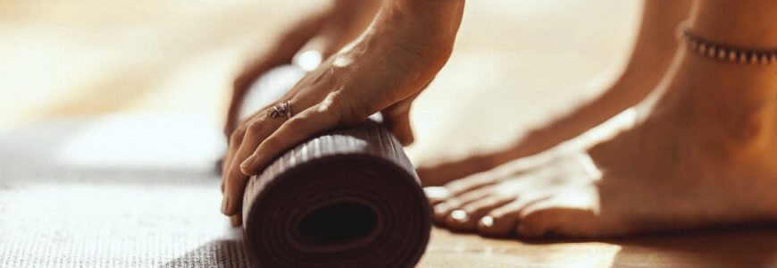 Frau, die Yoga-Matte ausrollt, für eine Yoga-Übung